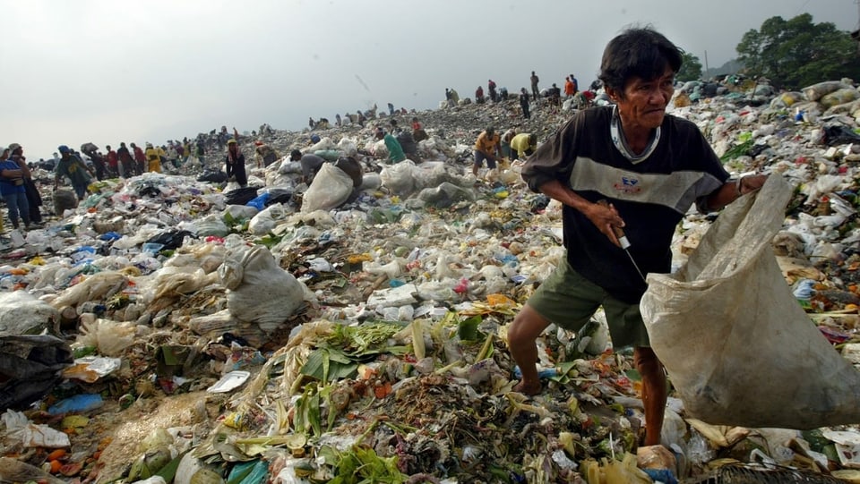 Ein Mann sammelt wiederverwertbaren Abfall und Nahrungsmittel für die Familie