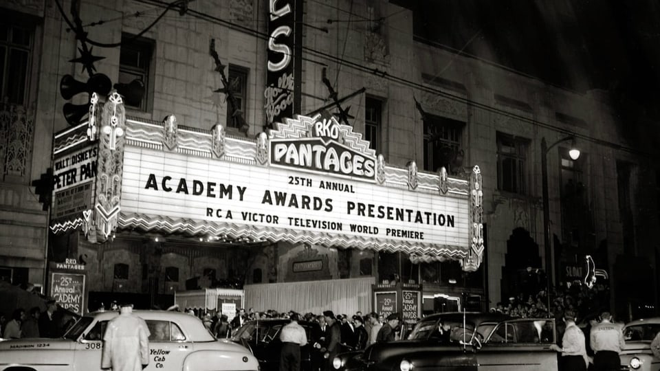 Eine Aufnahme aus den 1950-er Jahren, auf der man einen mit Lichtern ausgestrahlten  Kinoeingang sieht.
