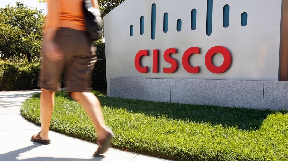 Frau läuft vor dem Logo der Firma Cisco vorbei.