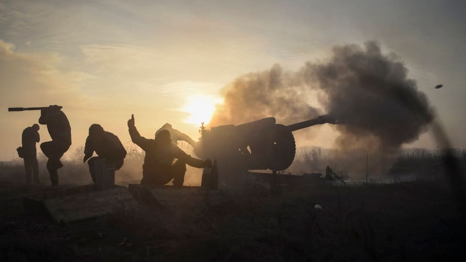 Symbolbild: Ukrainische Soldaten feuern im Gegenlicht eine Kanone ab.
