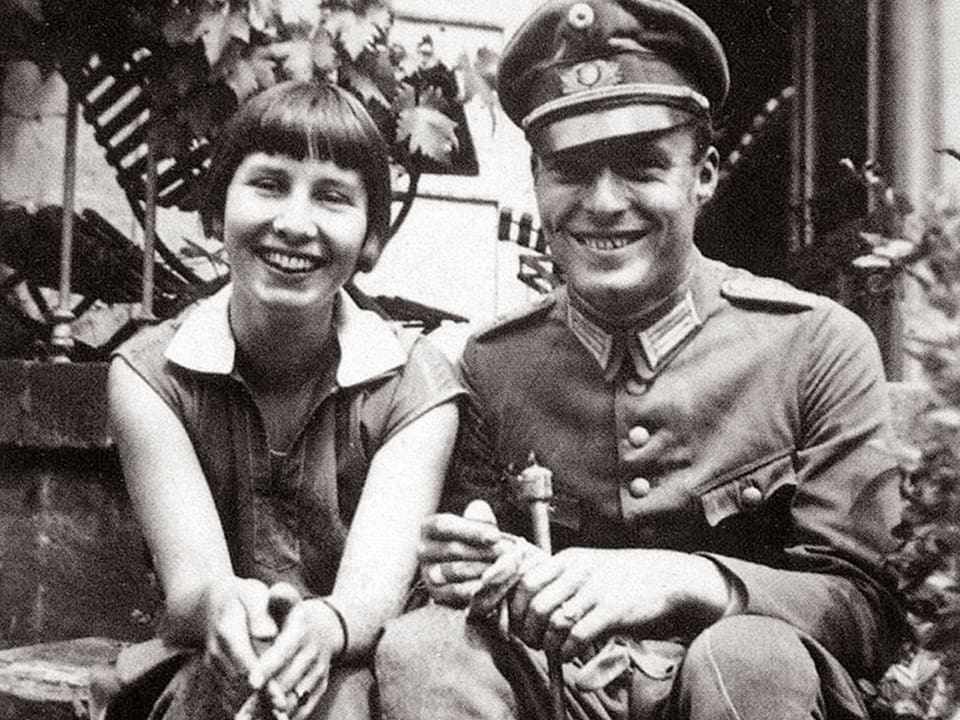 Historisches Foto: Eine junge Frau und ein junger Mann posieren lachend nebeneinander. Er trägt eine Soldatenuniform.