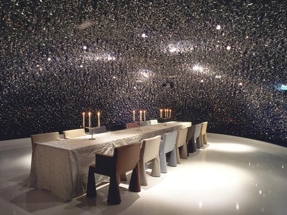 Tisch mit Kerzen vor «Sternenhimmel»-Wand