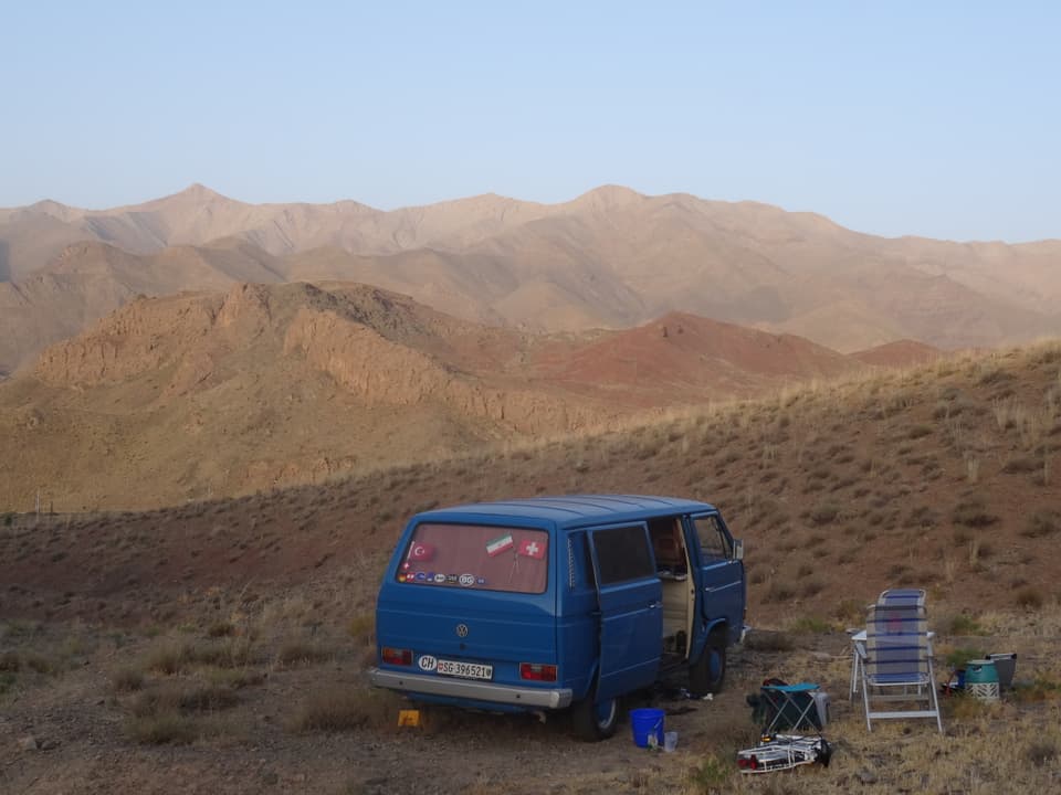 Das Bild zeigt einen blauen VW-Bus inmitten einer Wüstenregion.