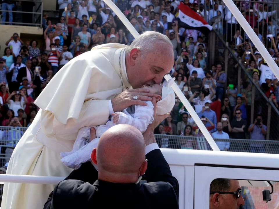 Franziskus küsst ein Kleinkind.