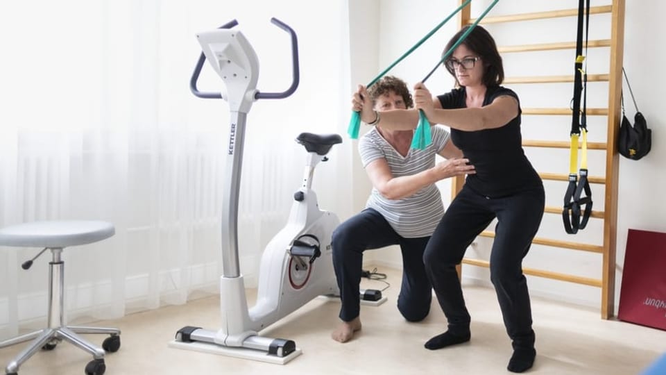 Eine Physiotherapeutin zeigt einer Patientin Übungen.