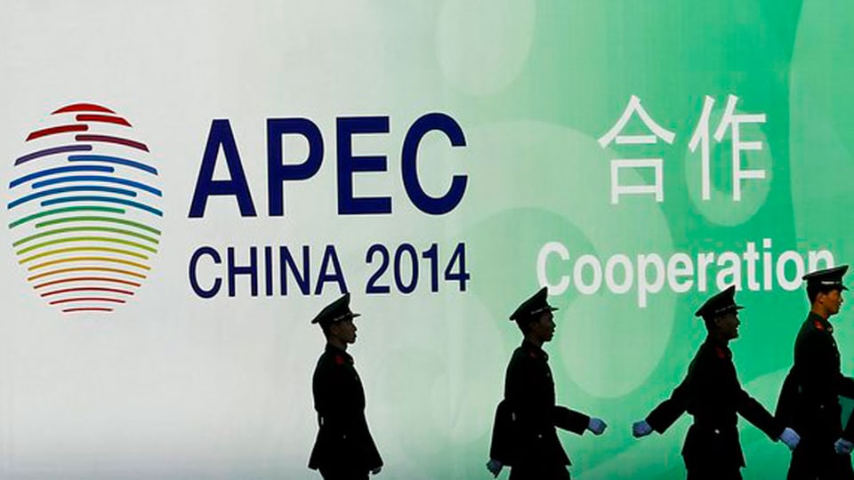 Silhouetten von Mitglieden der chinesischen Armee. Sie gehen vor einem Bild mit der Aufschrift «APEC, China 2014» vorbei.