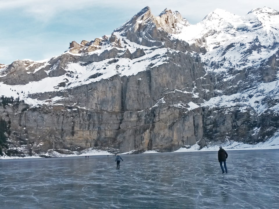 Schöner Bergpanorama, im Vordergrund Eisläufer auf dem See.