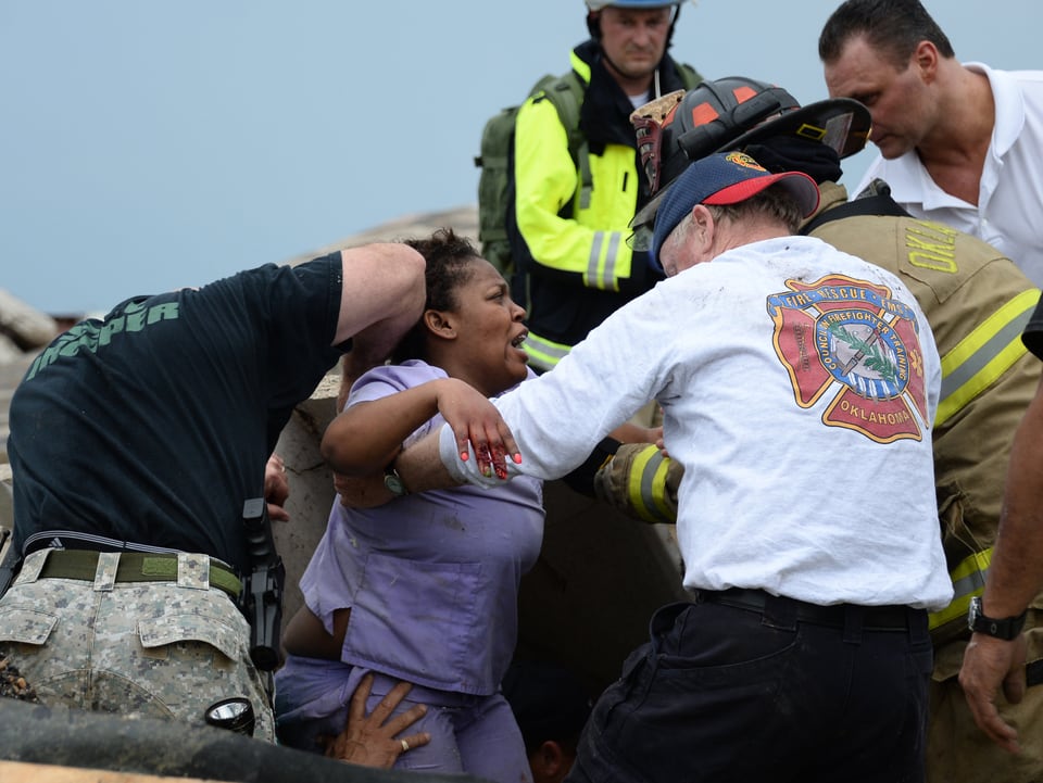 Helfer heben eine verletzte Frau aus den Trümmern.