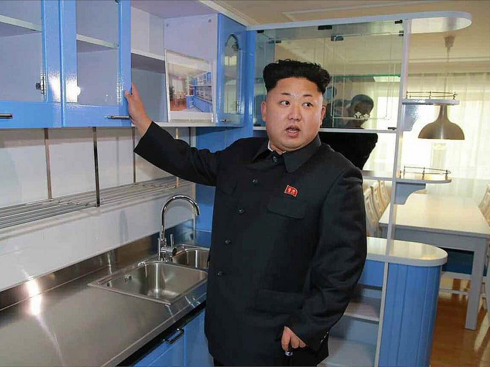 Kim öffnet ein Schränkchen in einer Küche.
