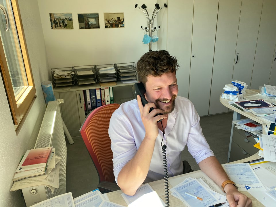 Ein Berater von «Infobest Palmrain» sitzt in seinem Büro am Telefon. 