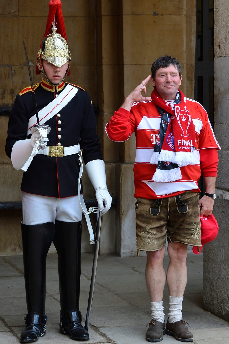 Ein Bayern-Fan in Lederhosen posiert neben einem Mitglied der königlichen Garde. 