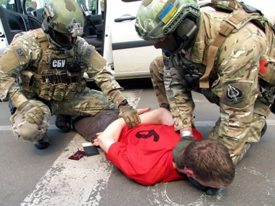 Zwei Sicherheitskräfte halten einen Mann am Boden fest