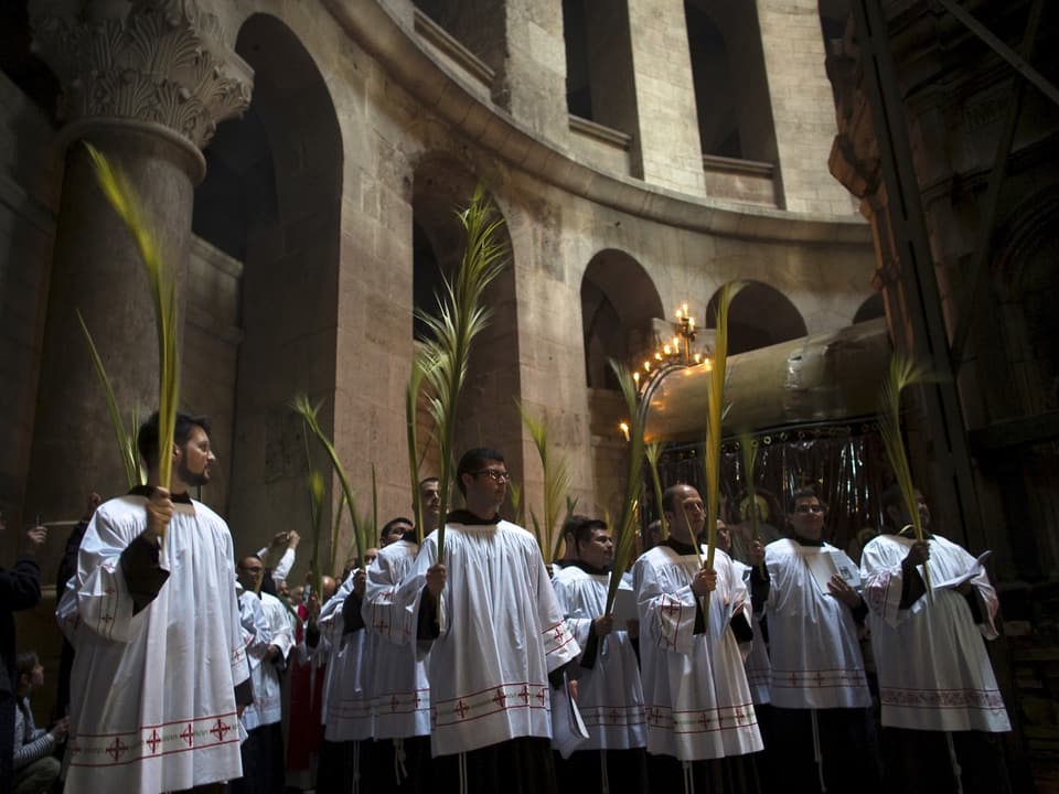 Menschen in weissen Gewändern mit Palmen in den Händen in Kirche