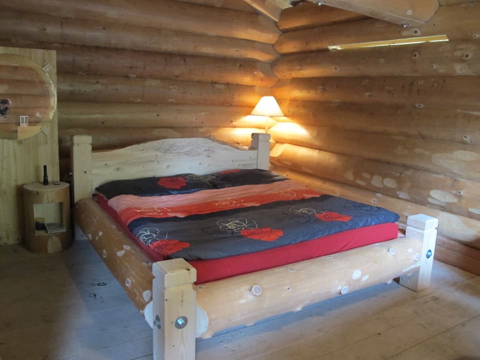 Bett mit farbigem Bezug in einer Hütte.