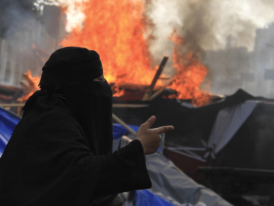 Eine Mursi-Anhängerin steht im brennenden Protestlager.