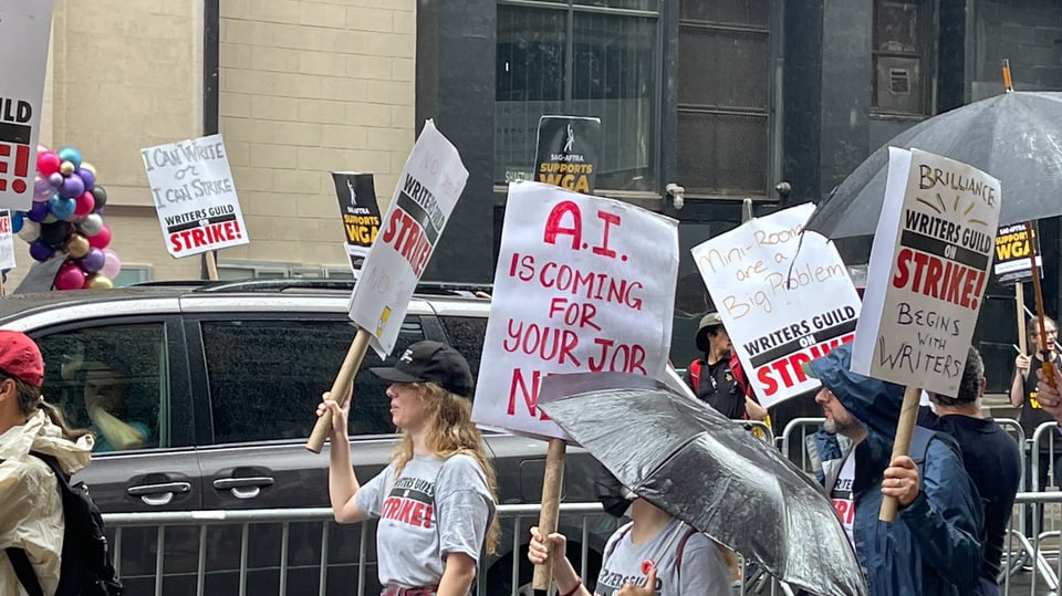 Demonstrierende mit Transparenten, auf einem steht: «AI is coming for your job next»