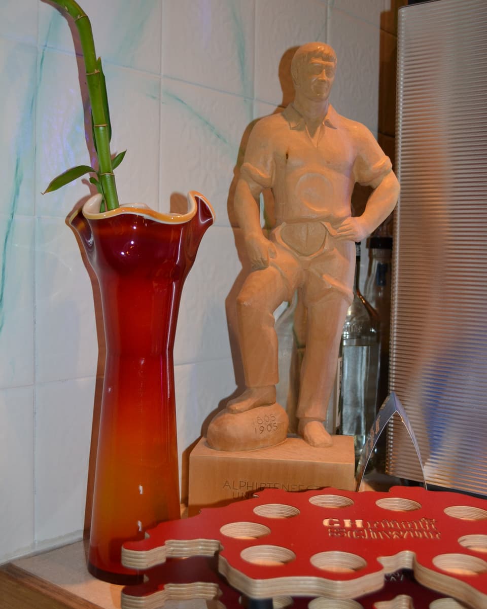 Eine Holzstatue neben einer Vase.