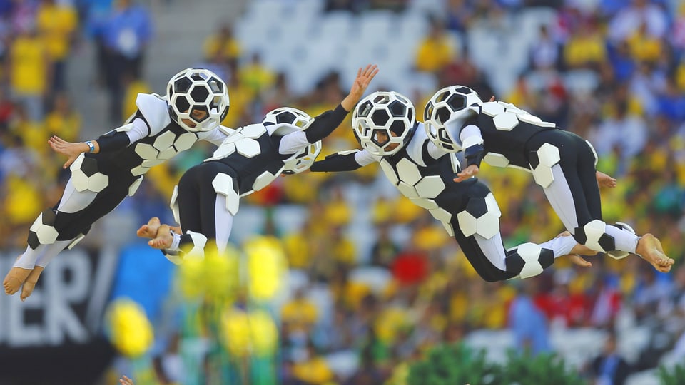 Schauspieler in Fussball-Kostümen fliegen durch die Luft.