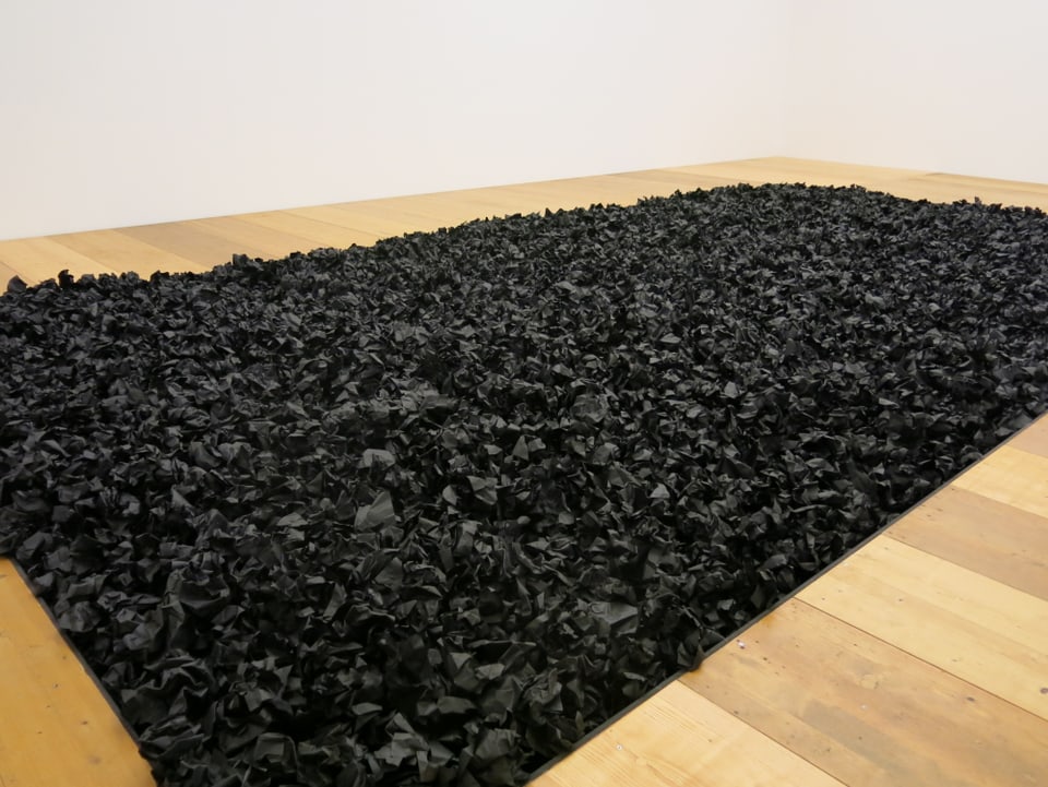 Schwarze Papierknäuel auf einer grossen Fläche im Kunstmuseum Thun.