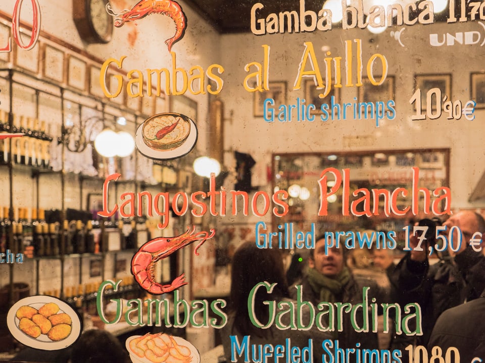 Durch die Fensterscheibe blickt man ins Innere eines spannischesn Restaurants.