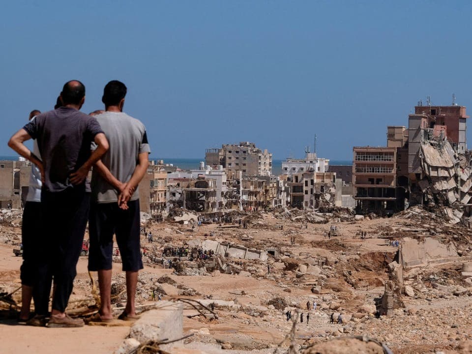 Menschen schauen auf die verwüstete Küstenstadt Derna in Lybien nach dem Sturm