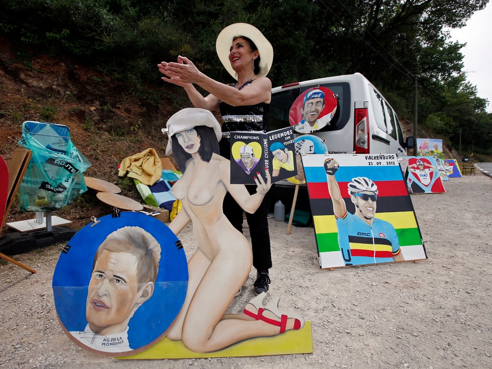 Artist and cyling fan Liliane stands behind a self-portrait and cheers riders during the 228.5 km fifth stage of the centenary Tour de France cycling race from Cagnes-Sur-Mer to Marseille July 3, 2013.