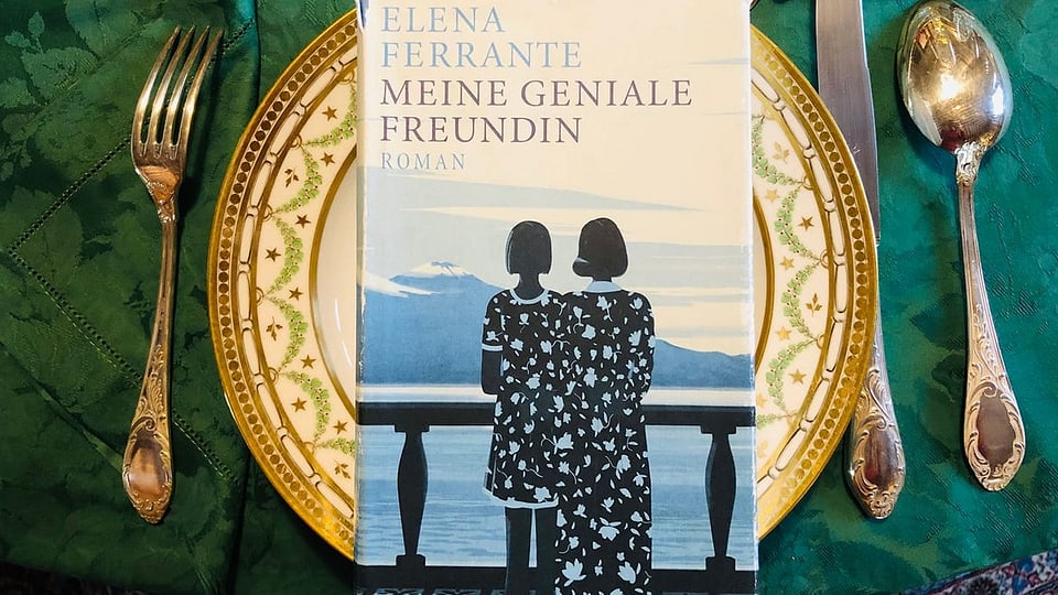 Der Roman «Meine geniale Freundin» von Elena Ferrante liegt auf einem goldenen Teller