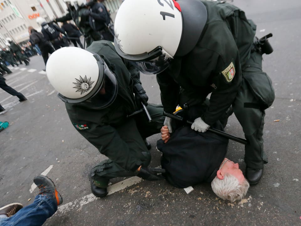 Polizisten verhaften einen am Boden liegenden Demonstranten