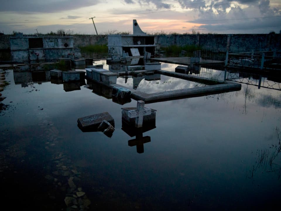 Ein Friedhof auf Kuba im Sonnenuntergang. Das Gräberfeld ist überflutet.