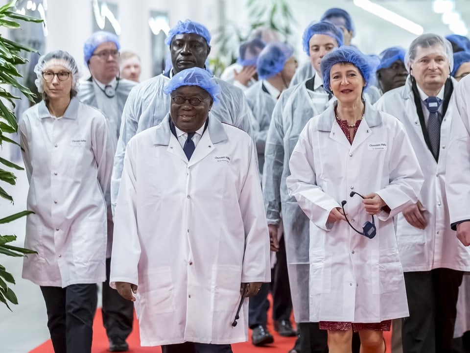 Ghanas Präsident Nana Addo Dankwa Akufo-Addo und Bundespräsidentin Simonetta Sommaruga besuchen eine Schokoladen-Fabrik und tragen dabei spezielle Schutzkleidung.