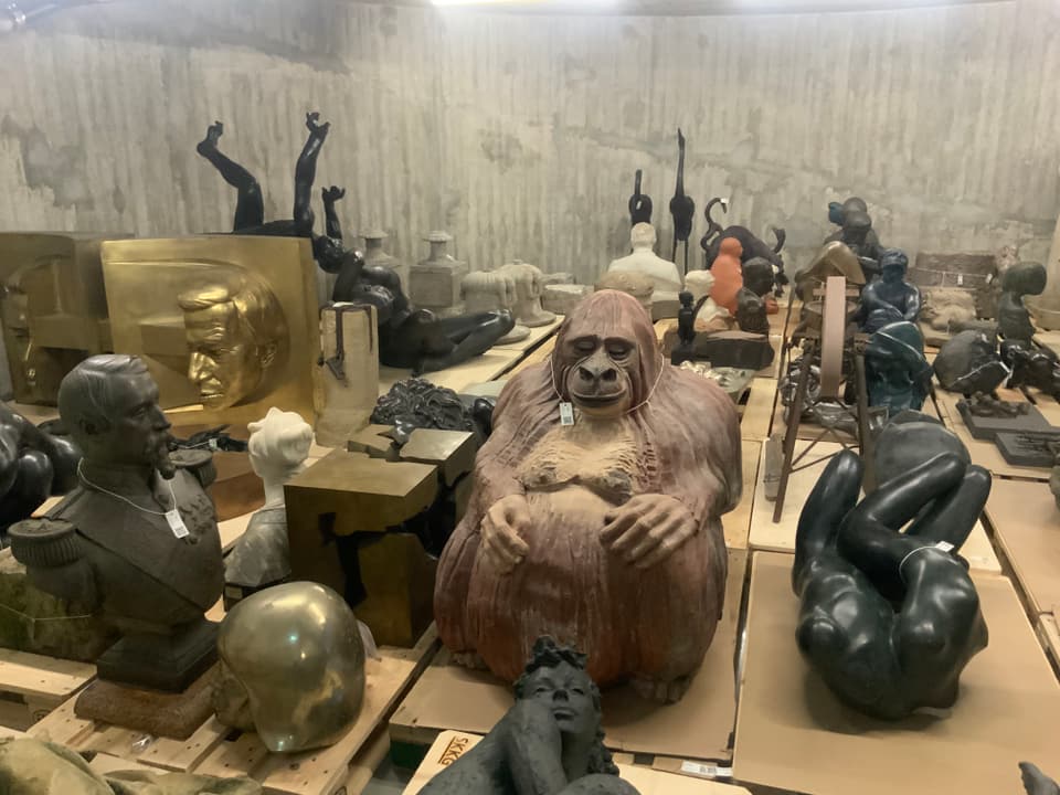 Auf dem Bild sieht man einen Kellerraum mit diversen Sammlungsgegenständen, in der Mitte eine Affen-Statue.