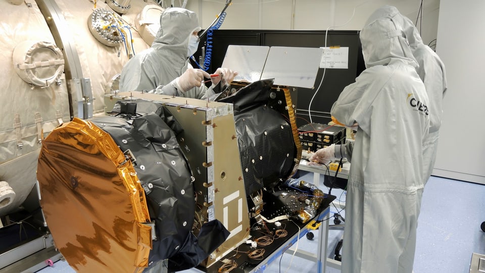 Wissenschaftler in Overalls arbeiten am Cheops-Satelliten