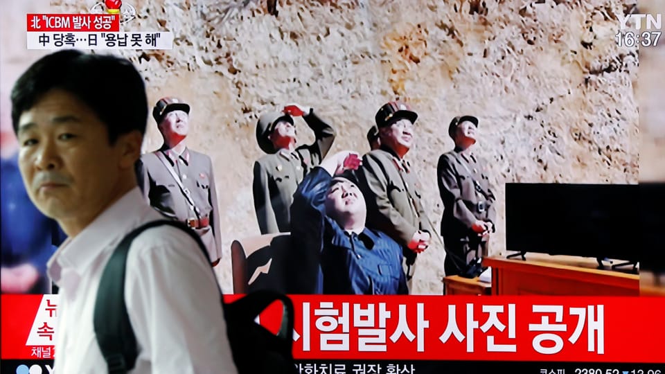 Ein Bildschirm zeigt Kim Jong Un und nordkoreanische Militärs, die nach oben schauen. 