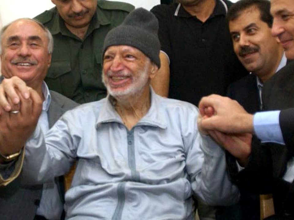 Der kranke Jassir Arafat umrundet von mehreren Männern.