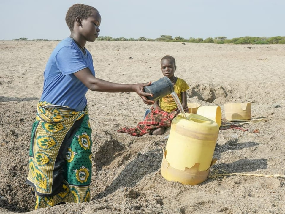 Zwei Kinder holen Wasser mit einem Kanister.