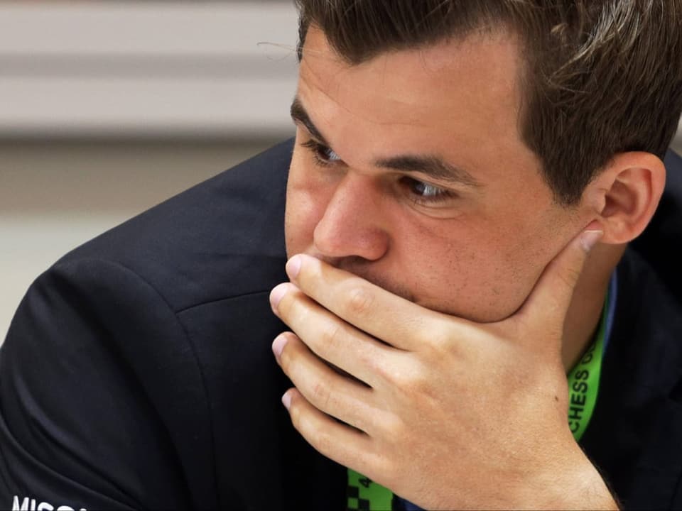 Magnus Carlsen hält sich die Hand vor den Mund