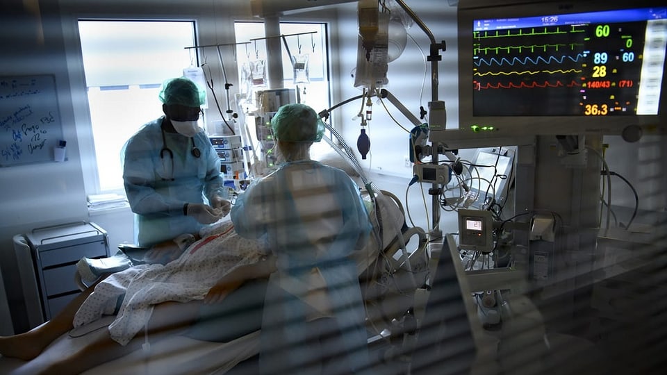 Intensivstation eines Spitals, Ärzte an einem Patientenbett