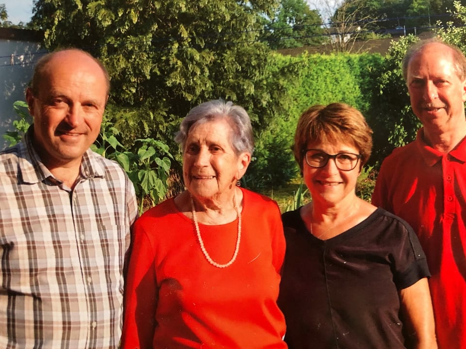 Familienfoto mit Mutter und drei erwachsenen Kindern.