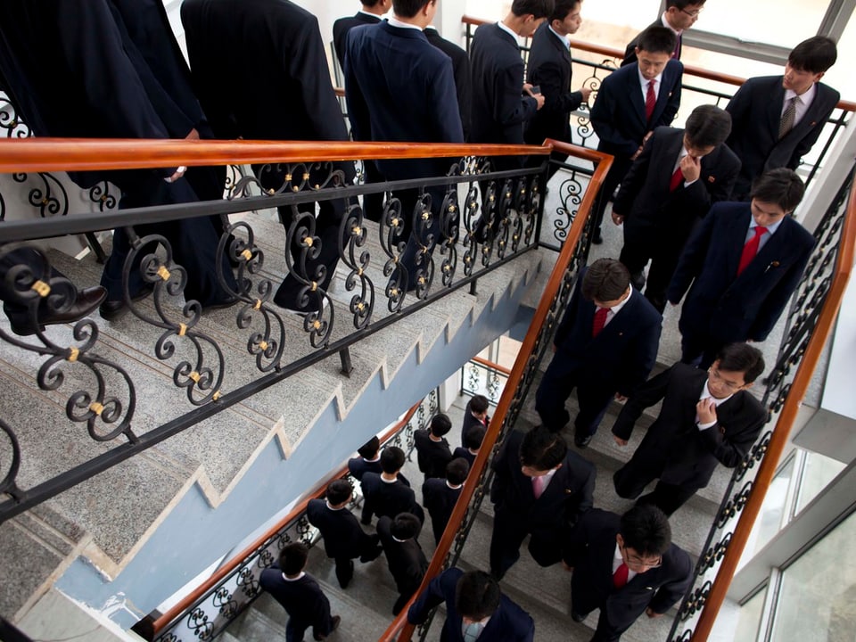 Studenten in Anzügen im Treppenhaus nach einer Vorlesung.