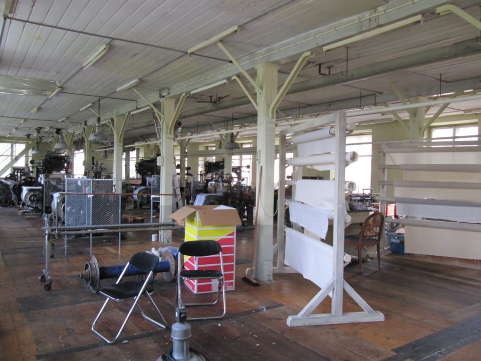Fabrikhalle, aufgeräumt mit Webstühlen im Hintergrund