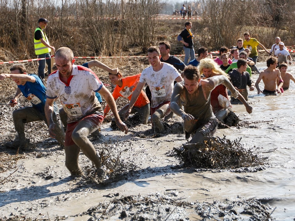 Teilnehmer am Survival Run in einem Schlammtümpel.