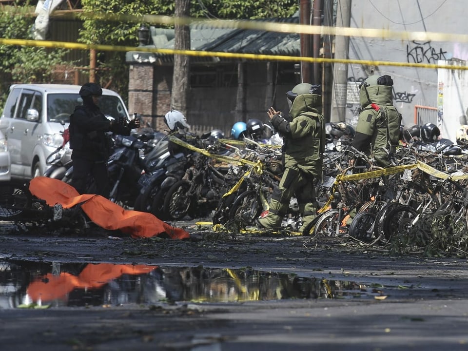 Polizisten vor zerstörten Motorrädern