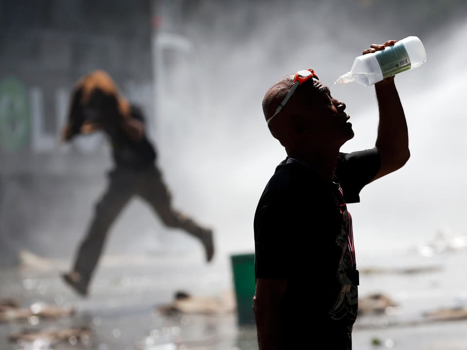 Ein Mann spült sich das gesicht mit Wasser aus einer Trinkflasche. (reuters)