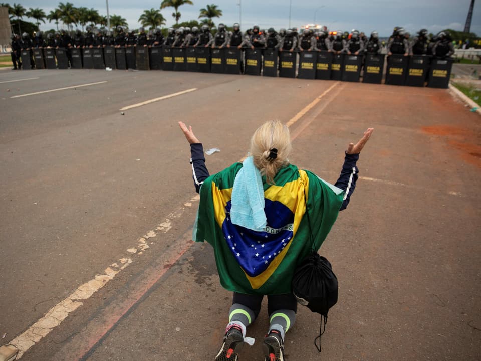 Eine Bolsonaro-Anhängerin kniet vor den angerückten Sicherheitskräften.