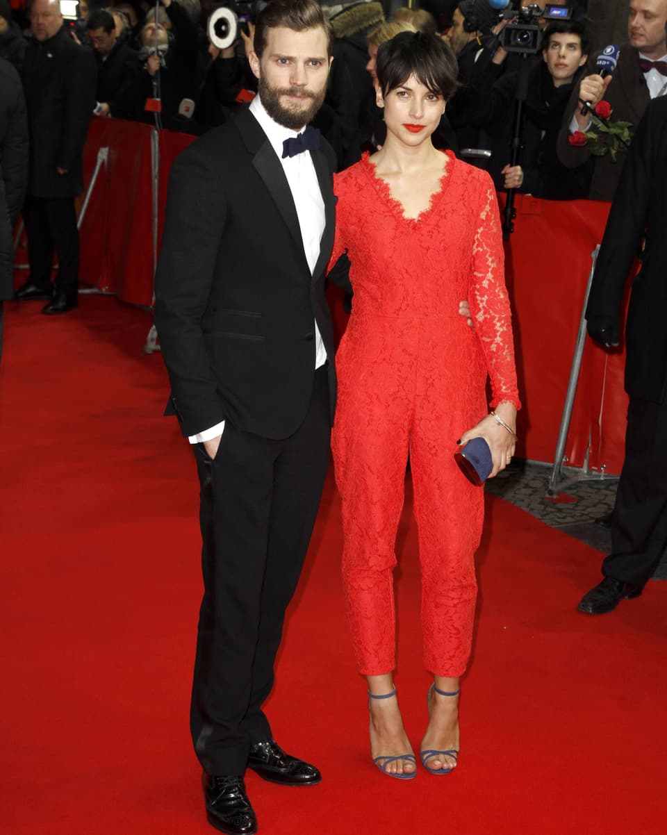 Der Hauptdarsteller mit seiner Frau im roten Anzug auf dem Teppich.