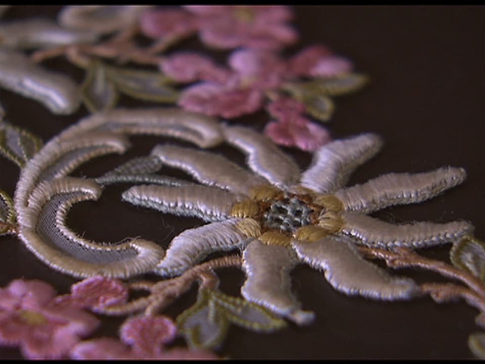 Eine gestickte Edelweiss-Pflanze mit langen Blütenblättern – ein Design unter dem Einfluss aus Fernost.