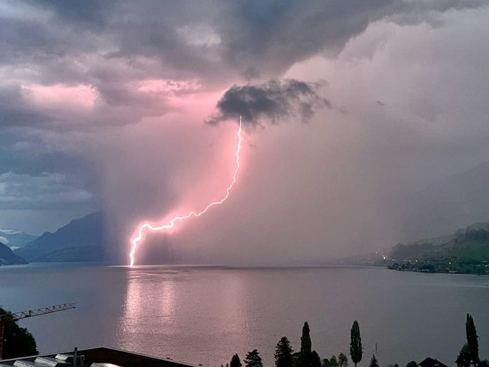 Dunkles Abendfoto mit Gewitter über See, es schlägt ein Blitz im See ein. 