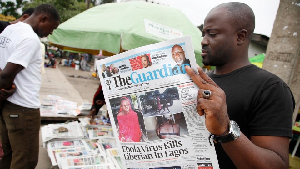 Mann liest Zeitung mit Schlagzeile des Ebola-Toten.
