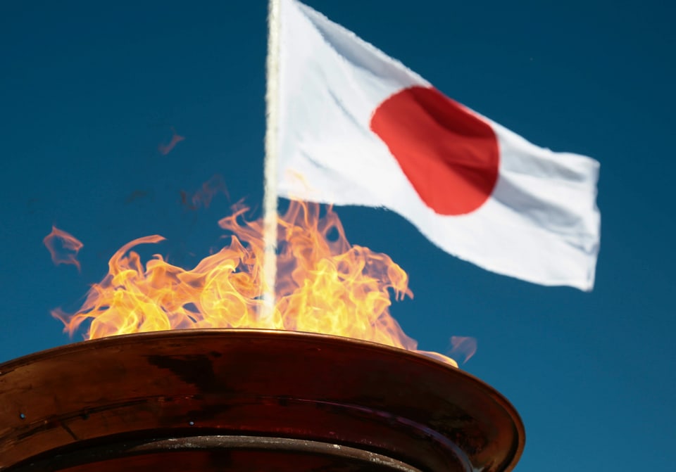 Japanische Fahne und das olympische Feuer im Hintergrund