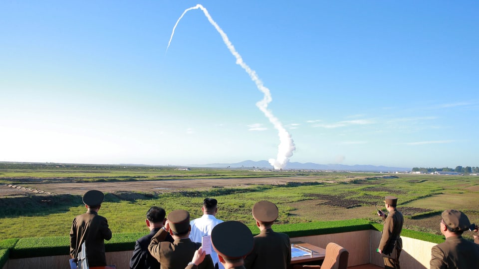 Un sieht von Militärs umringt einem Raketentest zu.